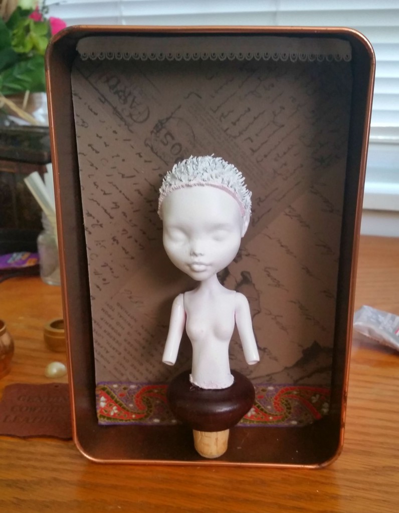 half-finished assemblage with a white spray-painted doll bust